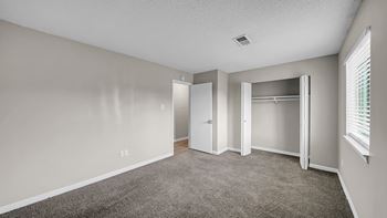 A room with a carpeted floor and a window with blinds.